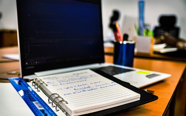 image of a computer and a pape notebook laying on it